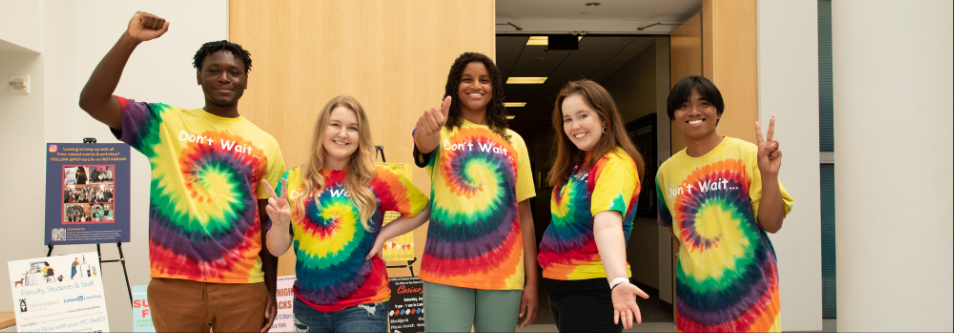 five students wearing tie-dye Don't Wait t-shirts in the Ruane Atrium